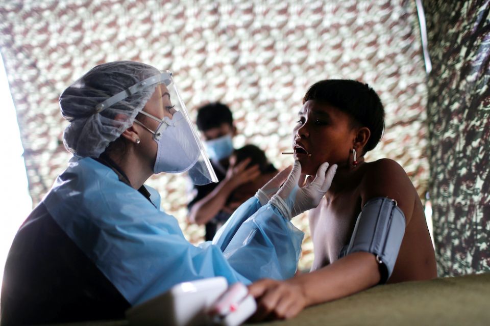A young Yanomami is examined by a member of a medical team with the Brazilian army in the state of Roraima July 1, 2020