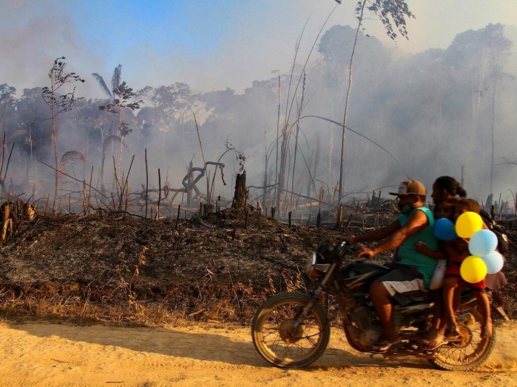 A family rides along a paved dirt road in an area scorched by fires near Labrea, Amazonas state, Brazil