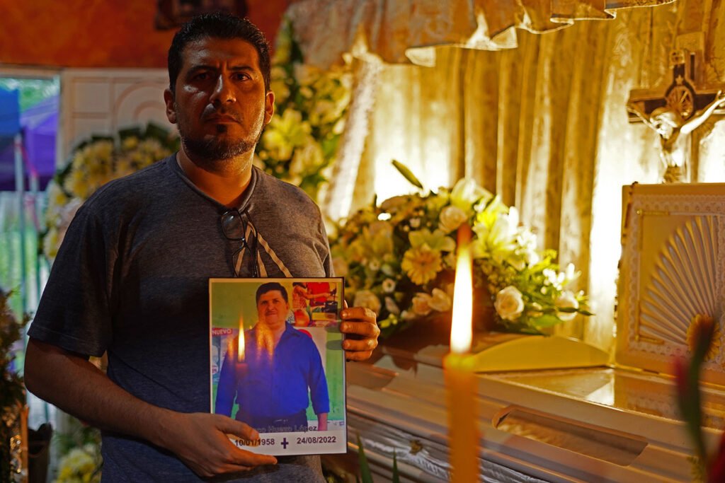 man holding photo of Don Paco in front of his casket