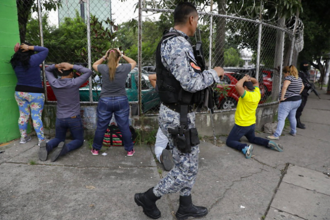 Policia standing behind detainees